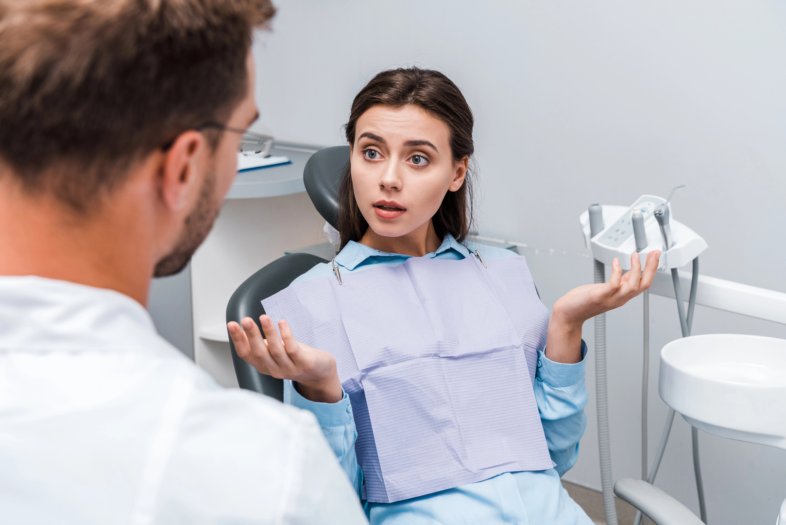 A photograph of a young woman wondering about the differences between a biological dentist and a traditional dentist